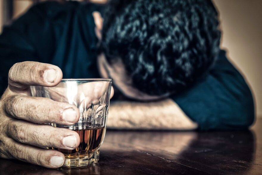 Drunk man holding a drink and sleeping on a table